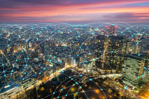 Aerial view of a city skyline at sunset, overlaid with digital connectivity lines, symbolizing urban networking and smart technology integration.